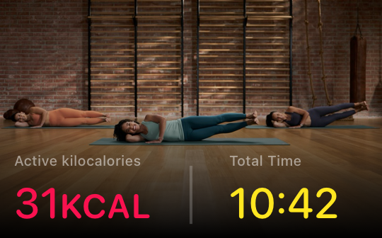 Three people performing plank exercises on mats in a brick gym, with text showing 31 kcal active calories and 10:42 total time.