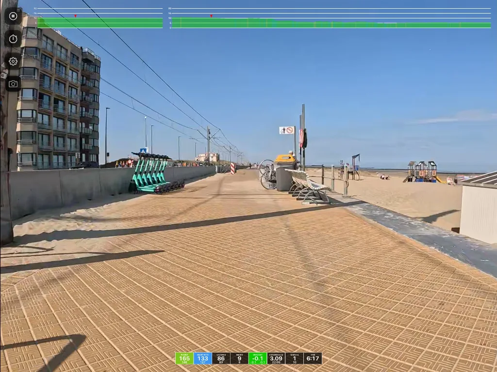 Beachfront boardwalk with brick paving, apartment building on left, playground equipment and beach beyond, clear blue sky, video editing interface visible at top.