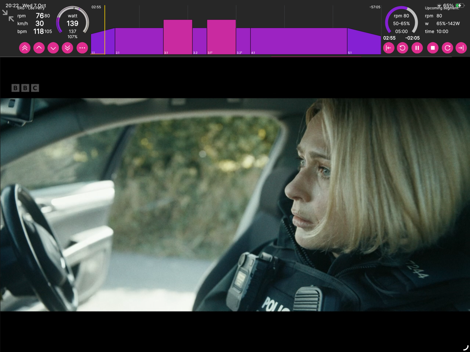 A person in police uniform sits in a car, looking ahead at the road during a BBC broadcast with fitness tracking overlay.